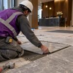 Installer laying stone tile in commercial lobby