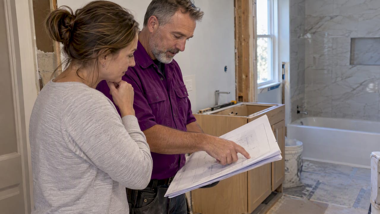 Homeowner and contractor reviewing bathroom permit plans